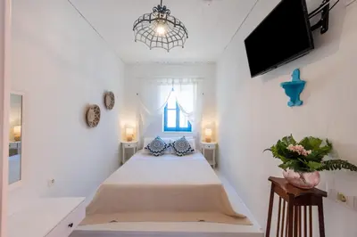 a bedroom with a bed and a tv on the wall at SUN PETRADI Tradition & Luxury in Koskinou