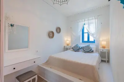 a white bedroom with a bed and a window at SUN PETRADI Tradition & Luxury in Koskinou