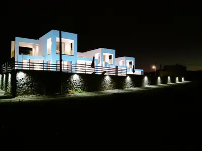 a white building with lights on a street at night at Alpha Villas in Gennadi