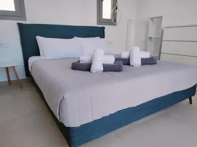 a large bed with white pillows and a blue headboard at Alpha Villas in Gennadi