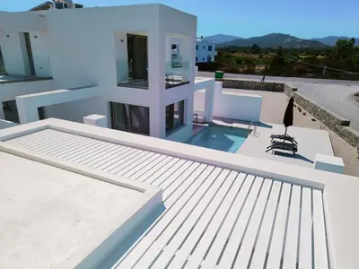 a white house with a swimming pool on a roof at Alpha Villas in Gennadi