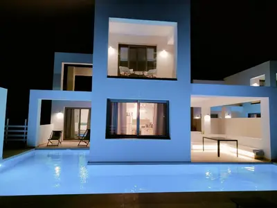a villa with a swimming pool at night at Alpha Villas in Gennadi