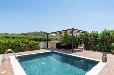 a swimming pool with a pergola next to a house at Dioni Pool House in Ialyssos
