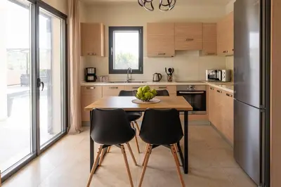 a kitchen with a wooden table and black chairs at Dioni Pool House in Ialyssos
