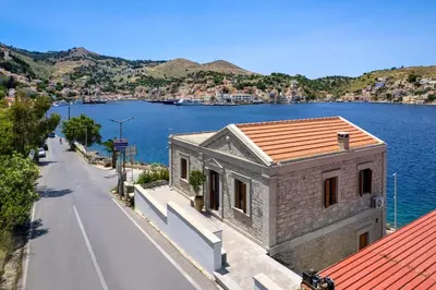 a building on the side of a road next to a body of water at Petalo House in Symi