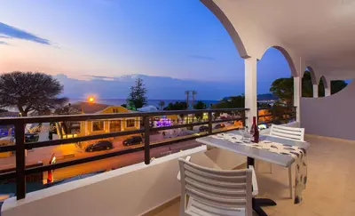 a balcony with a table and chairs and a train at Sunny Days Hotel in Ixia