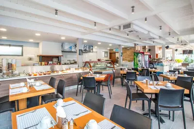 a restaurant with tables and chairs and a kitchen at Sunny Days Hotel in Ixia
