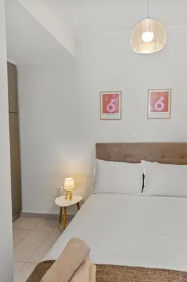 a bedroom with a large white bed with a table at Rhodian Filoxenia in Rhodes Town