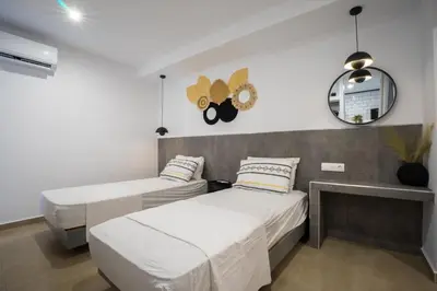 a bedroom with two beds and a clock on the wall at Mousikorama Apartments in Faliraki