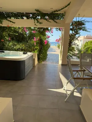 a patio with a hot tub and a view of the ocean at Amaryllis Beach House in Lardos