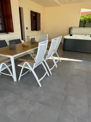 a dining room with a table and white chairs at Amaryllis Beach House in Lardos