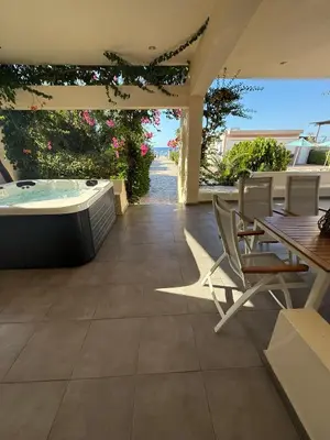a patio with a hot tub and a table and chairs at Amaryllis Beach House in Lardos