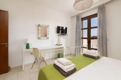 a bedroom with a bed and a desk and a window at Lindos Aeonian Villas in Líndos