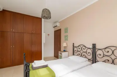 a bedroom with two beds and wooden cabinets at Lindos Aeonian Villas in Líndos