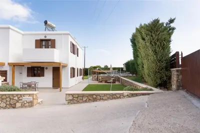 a white house with a patio and a yard at Lindos Aeonian Villas in Líndos