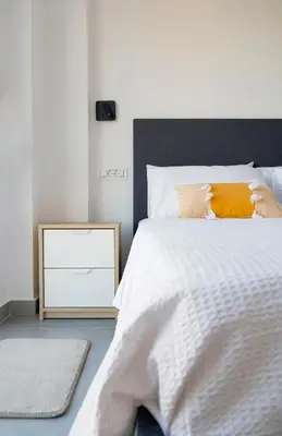 a bedroom with a white bed and a night stand at Zen Beach House Faliraki in Faliraki