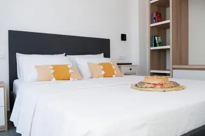 a white bed with orange pillows on top of it at Zen Beach House Faliraki in Faliraki