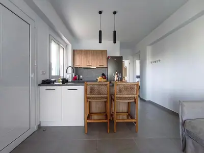 a kitchen with white cabinets and a table and chairs at Zen Beach House Faliraki in Faliraki