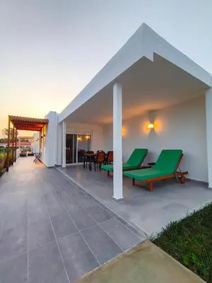 an outdoor patio with green chairs and tables at Zen Beach House Faliraki in Faliraki