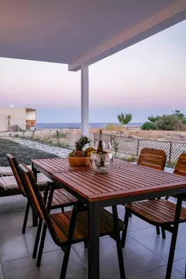 a wooden table and chairs with a view of the desert at Zen Beach House Faliraki in Faliraki