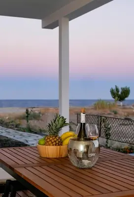 a bottle of wine and a bowl of fruit on a table at Zen Beach House Faliraki in Faliraki
