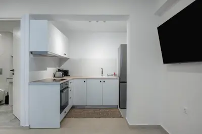 a kitchen with white cabinets and a flat screen tv at Blue Di Mare Villas in Lachania