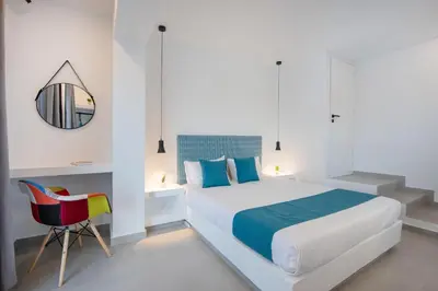 a white bedroom with a bed and a chair at Blue Di Mare Villas in Lachania
