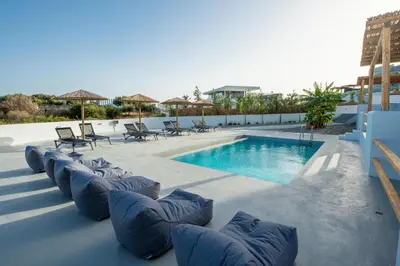 a pool with chaise lounges and chairs next to a pool at Blue Di Mare Villas in Lachania