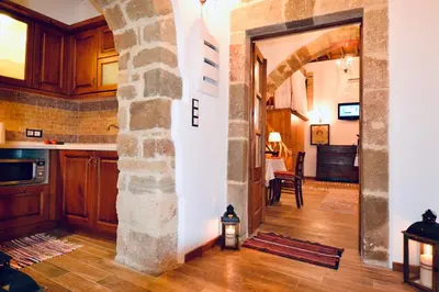 a kitchen with a stone archway and a living room at Villa Patitiri Traditional House with hot tub in Archangelos