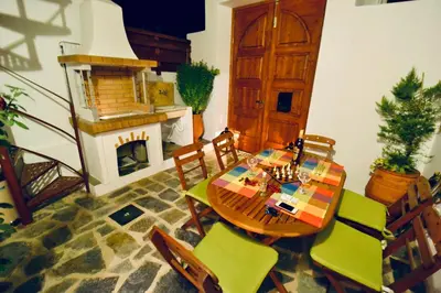 a dining room with a table and chairs and a fireplace at Villa Patitiri Traditional House with hot tub in Archangelos