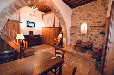 a living room with a wooden table and a stone wall at Villa Patitiri Traditional House with hot tub in Archangelos