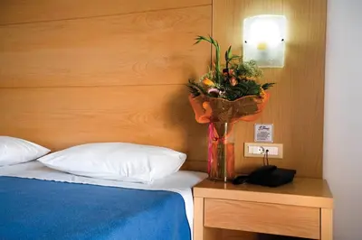 a vase of flowers on a table next to a bed at Pefki Islands in Pefki Rhodes