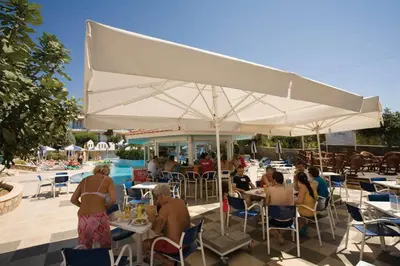 a group of people sitting at tables under a large white umbrella at Pefki Islands in Pefki Rhodes