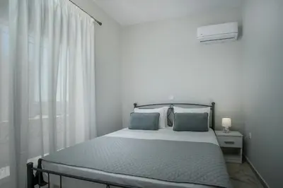 a white bedroom with a bed and a window at Anastasia Luxury House in Afantou