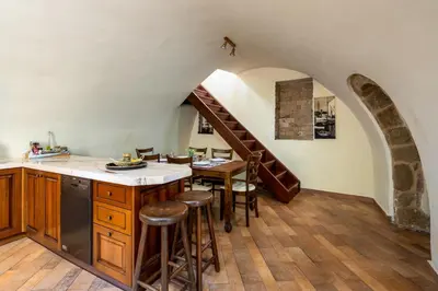 a kitchen with a staircase and a table with stools at Suite del Capitano in Rhodes Town