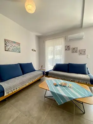 a living room with a couch and a table at Cozy blue in Ialyssos