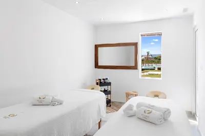 a white room with two beds and a mirror at Alia Beachfront Suites and Spa in Haraki