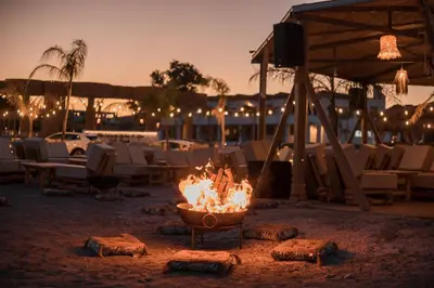 a fire pit on a beach with tables and chairs at Alia Beachfront Suites and Spa in Haraki