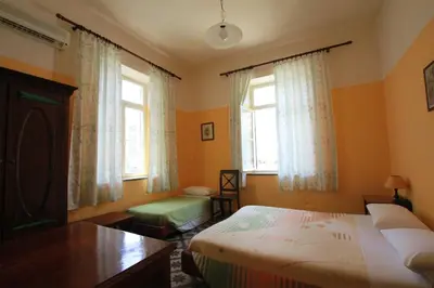 a bedroom with a bed and a desk and two windows at Hotel Anastasia in Rhodes Town