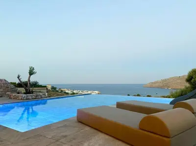 a swimming pool with a couch and the ocean at Alindo Villa II, in Lindos area in Líndos