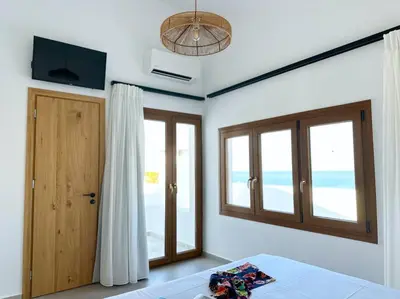 a bedroom with a bed and a door and windows at Alindo Villa II, in Lindos area in Líndos