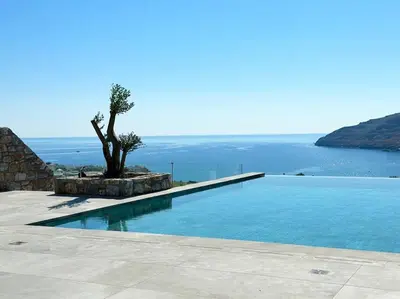 a swimming pool with a tree and the ocean at Alindo Villa II, in Lindos area in Líndos