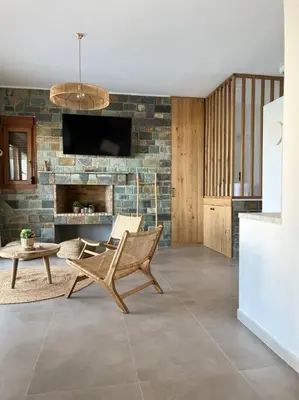 a living room with a chair and a stone wall at Alindo Villa II, in Lindos area in Líndos