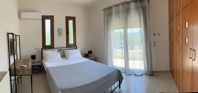 a bedroom with a bed and a large window at Luna's Summer House in Kremasti
