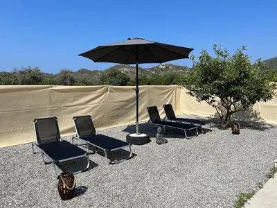 three chairs and an umbrella in front of a tent at Luna's Summer House in Kremasti