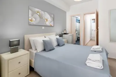 a white bedroom with a large bed and a television at Elena in Symi