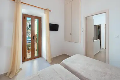 a white bedroom with a bed and a mirror at Elena in Symi