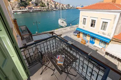 a balcony with chairs and a view of the water at Elena in Symi