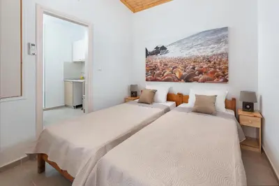 two beds in a room with a painting on the wall at Elena in Symi