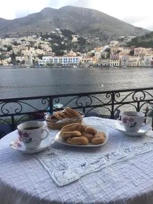 a table with a plate of pastries and cups of coffee at Nikolitsi Studios in Symi